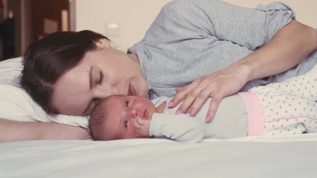 Affectionate mother kissing her baby on bed