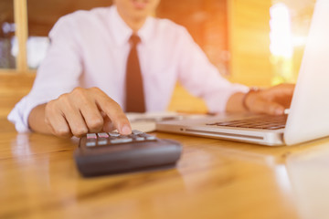 Businessman analyzing investment charts with calculator laptop. Accounting and technology in office.Business people using laptop at office,Analyze plans.selective focus,vintage color