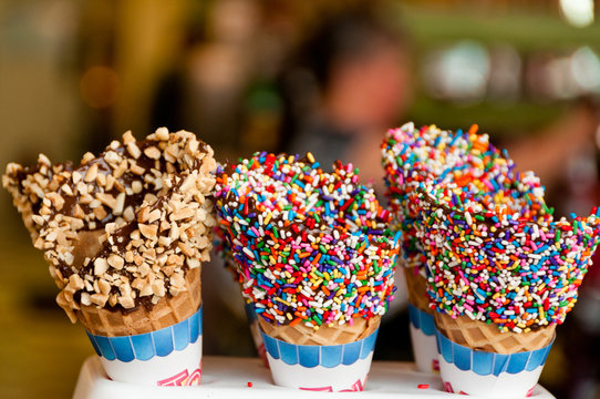 Close up of Three Ice Cream Cones with Scoops Covered with Different Types of Sprinkles.  Blurred background of a Soda Jerk.