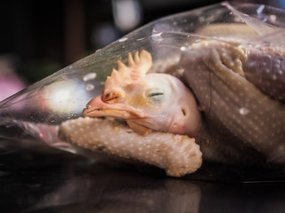 a dead chicken head in a vacuum plastic bag on a market for sale
