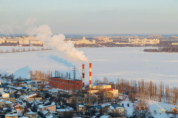 Winter Voronezh cityscape at sunny evening.  Frozen river, smoking pipes of thermal power plant