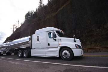 Obraz premium Big rig semi truck transporting liquid cargo in stainless steel tank on the winding road