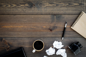 Writer profession. Retro concept. Notebook, pen, inkpot, coffee near crumpled paper balls on dark wooden background top view copy space