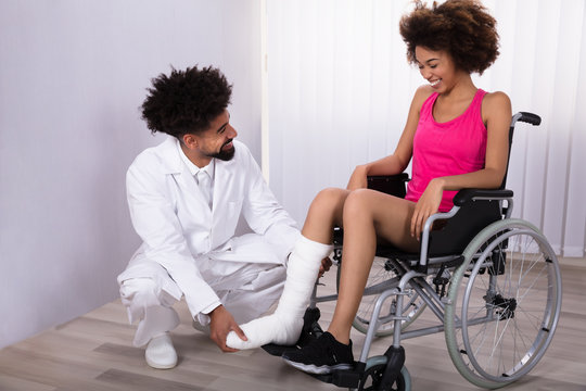 Physiotherapist Examining Leg Of Female Patient