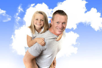young attractive and athletic father carrying on his back young beautiful and blond daughter having fun together posing isolated on blue sky