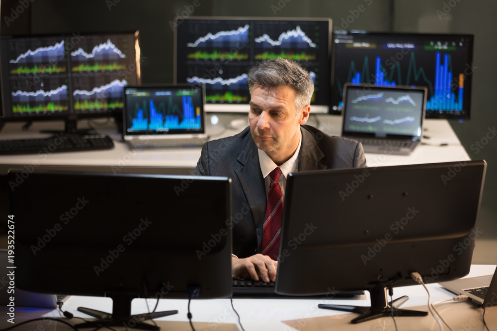 Poster stock market broker looking at multiple computer screen