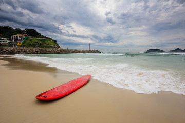 red surfboard laying on shorebreak