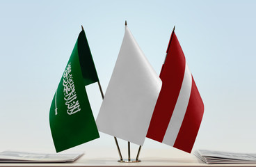 Flags of Saudi Arabia and Latvia with a white flag in the middle