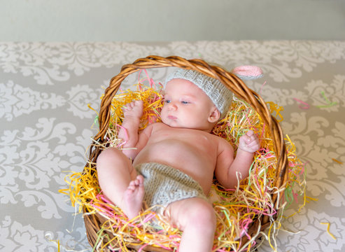 newborn baby with bunny ear hat laying in Easter basket