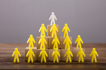 White Figure Standing On Top Of Yellow Human Figures