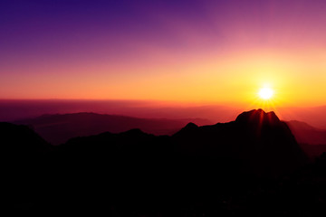A stunning sunset or sunrise scene of silhouette mountain peaks and purple ridges with the twilight background, the purple sky and the pink-yellow skyline, captured at chiangmai, thailand