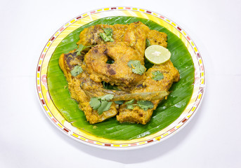 Fish masala curry served on banana leaf with lemon and coriander. Rohu fish is a popular Bengali Indian food.