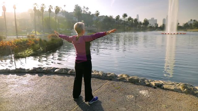 71 year old woman stretching after her morining walk in the park.