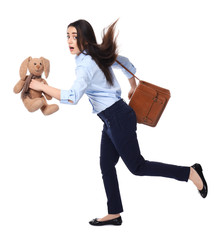 Young businesswoman with bag and bunny toy running on white background