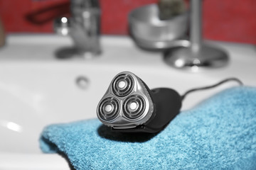 Electric shaver for man and towel on sink