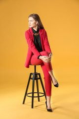 Beautiful fashionable woman in elegant suit on color background