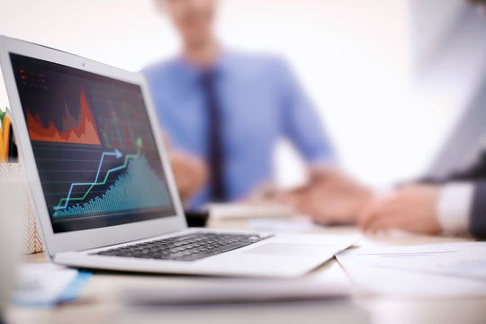 Laptop with stock data on table in office. Financial trading concept