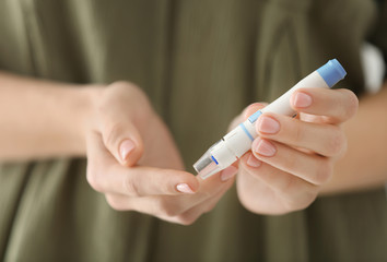 Diabetic woman taking blood sample with lancet pen, closeup
