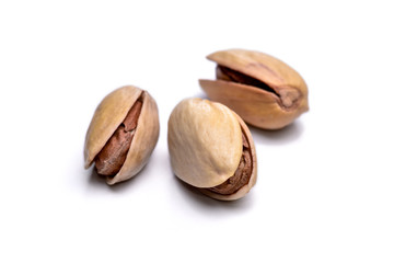 Three roasted pistachio nuts (Pistacia vera) isolated on white background