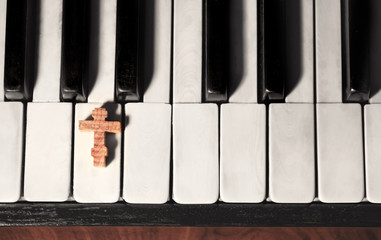 Wooden cross on piano keys, top view