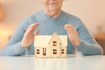 Senior woman with house model at table. Home care concept