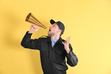 Male security guard with megaphone on color background