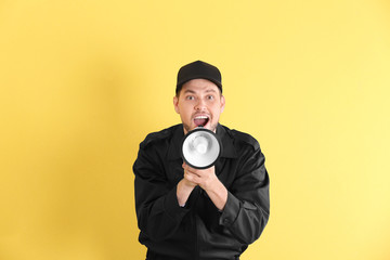 Male security guard with megaphone on color background