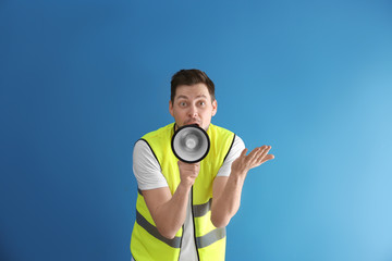 Worker with megaphone on color background