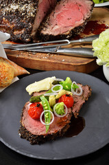 Rib eye steak with vegetables on black plate
