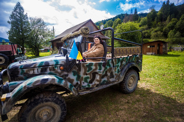 Fototapeta premium Happy senior tourist woman travel by car in mountain forest in autumn with dramatic sky on background