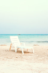 One beach chair on a white sand against the ocean view. Peaceful, calm place, relaxation concept. Vitage filter toned effect. Copy space for text