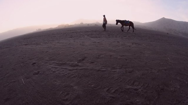 Horseman walking with his horse in the morning near Mount Bromo, Indonesia