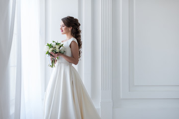 Fototapeta premium attractive happy bride posing in traditional dress with wedding bouquet