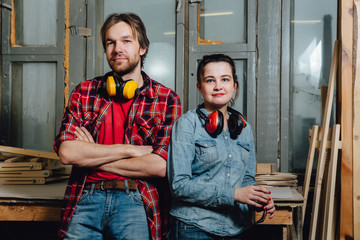 Portrait of carpenters in the workshop. A man and a girl, leaned back and posed.