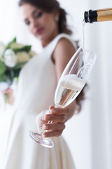 selective focus of bride holding glass of champagne