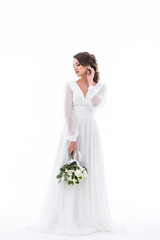 Fototapeta na wymiar tender bride posing in elegant dress with wedding bouquet, isolated on white