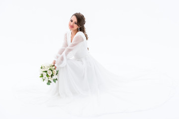 Fototapeta na wymiar smiling bride in elegant dress holding wedding bouquet, isolated on white