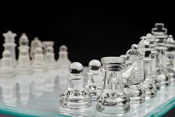 Szachy, szklana szachownica z pionkami na czarnym tle