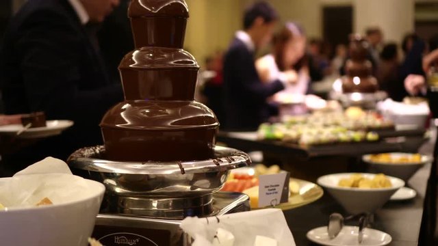Chocolate fountain at wedding dinning party with hands dipping