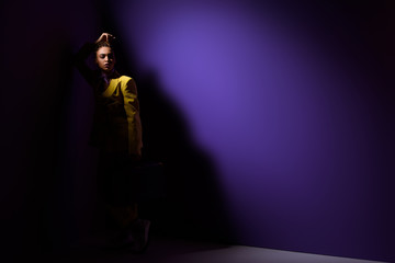 Fototapeta na wymiar fashionable elegant african american girl posing in dark, on trendy ultra violet background