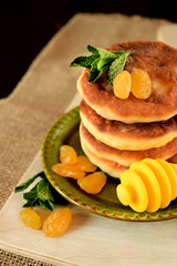 Cottage cheese pancakes, syrniki decorated with raisins on a little plate
