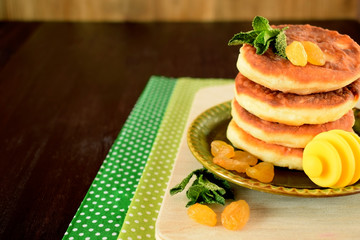 Cottage cheese pancakes, syrniki decorated with raisins on a little plate