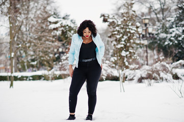 Stylish african american plus size model with mobile phone at hand  at winter snowy day.