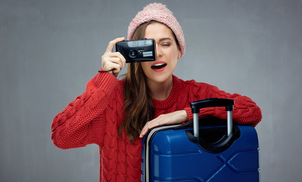 Happy woman traveler with travel case taking pictures with camer