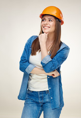 Smiling woman wearing builder helmet standing with crossed arms.