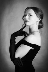 Beautiful girl in evening dress and long gloves. Black and white portrait in studio