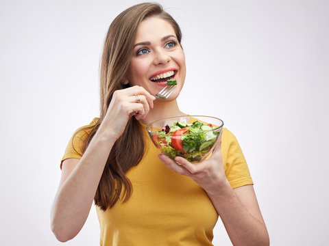 portrait of young woman dressed in yellow eating green salad.