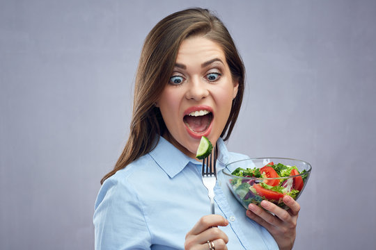 Shocking woman eating salad with fork.