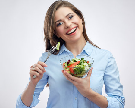 Smiling woman eating salad from glass bowl.