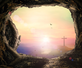 Resurrection of Easter Sunday concept: The cross and empty tomb stone over mountain sunrise background 